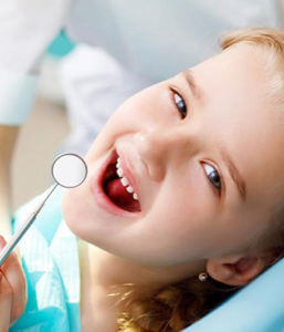 Young girl smiling at camera with mouth open for dental cleaning