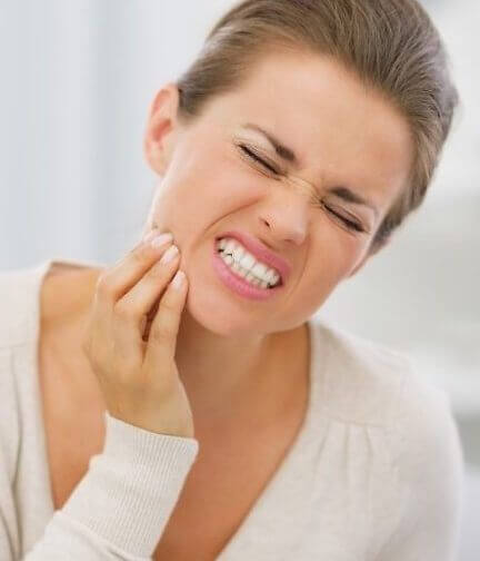 Woman wincing because of sensitive teeth